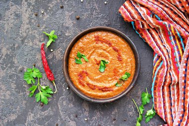 İştah açıcı humus kırmızı mercimek ve koyu beton arka planda kil kasede kırmızı biber..