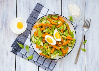 Kızarmış patates ya da balkabağı salatası roka, salatalık ve kaynamış yumurta açık ahşap bir zeminde. Tatlı patates tarifleri. Sağlıklı yemek. 