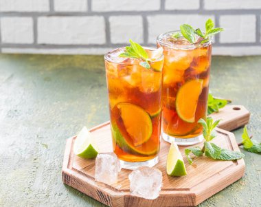 Serinletici içecek, yeşil beton arka planda tahta bir tahtanın üzerinde limon dilimli buzlu çay. Yaz içkileri. Hafif içecekler.