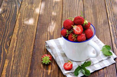 Tahta arka planda beyaz kupada taze organik çilekler. Çilek toplayın. Yaz konsepti.