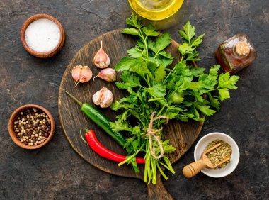 Chimichuri için hazırlanan malzemeler, Arjantin yeşil biftek sosu taze maydanoz, sarımsak, zeytinyağı ve koyu beton arka planda kekik. Sos tarifleri. Arjantin mutfağı