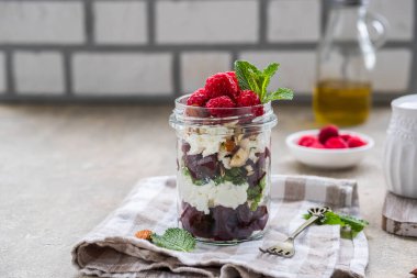 Sağlıklı bir salata pancar, krem peynir ya da süzme peynir, fındık ve ahududu açık beton arka planda cam bir kavanozda. Salata tarifleri. Kavanoz salatası.