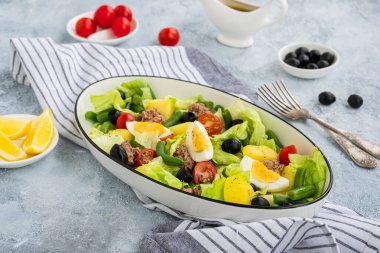 Amerikan versiyonunda konserve ton balığı, haşlanmış patates ve gri beton tabakta oval beyaz bir tabakta yeşil kuşkonmaz fasulyesi. Salata tarifleri.