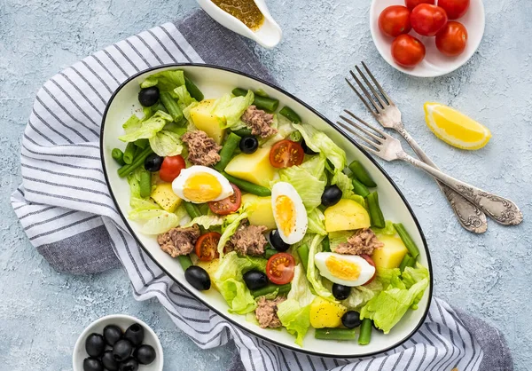 Amerikan versiyonunda konserve ton balığı, haşlanmış patates ve gri beton tabakta oval beyaz bir tabakta yeşil kuşkonmaz fasulyesi. Salata tarifleri.