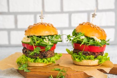 Fasulye burgerli vejetaryen hamburgerler ve ev yapımı bir fincan tabağında hafif beton arka planda taze sebzeler. Hamburger tarifleri. Amerikan yemekleri.