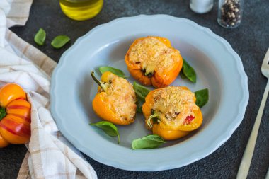 Koyu beton arka planda gri bir tabakta ricotta peyniri ve sebzelerle doldurulmuş sarı biberler. Doldurulmuş sebze tarifleri. İtalyan yemeği.