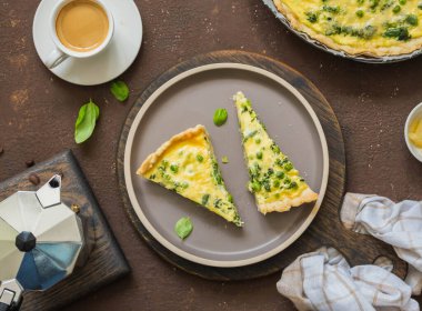 Ispanaklı dilimlenmiş kiş turtası, yeşil bezelye, kuşkonmaz fasulyesi ve kahverengi beton arka planda seramik tabakta yumurta. Fransız mutfağı. Tuzlu hamur işi tarifleri