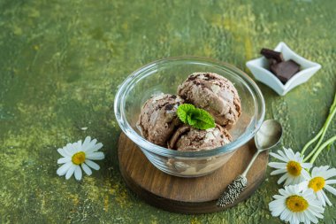 Üç kepçe ev yapımı çikolatalı dondurma yeşil beton arka planda cam bir kasede. Dondurma tarifleri.