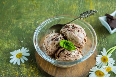 Üç kepçe ev yapımı çikolatalı dondurma yeşil beton arka planda cam bir kasede. Dondurma tarifleri.