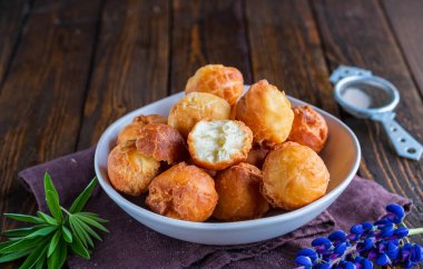 Kahverengi ahşap arka planda seramik bir kasede yuvarlak kızarmış çörekler. Yağda pişirme.