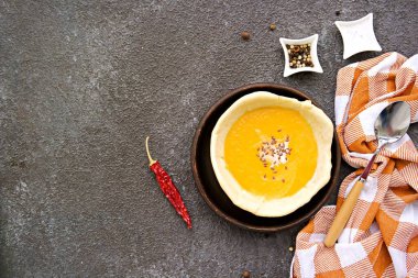 Kahverengi tepside, gri beton arka planda yenilebilir ekmek tabağında balkabağı püresi çorbası. Balkabağı tarifleri. Şükran Günü.
