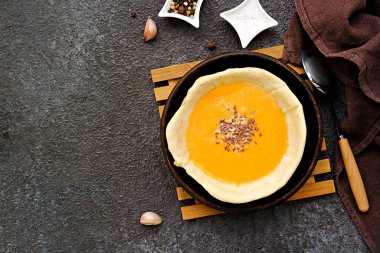 Kahverengi tepside, gri beton arka planda yenilebilir ekmek tabağında balkabağı püresi çorbası. Balkabağı tarifleri. Şükran Günü.