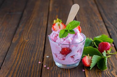 Kahverengi ahşap arka planda bardakta taze çilekli ev yapımı çilekli dondurma. Ev yapımı dondurma tarifleri.