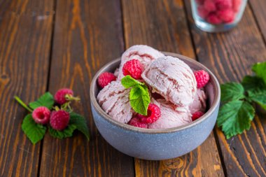 Kahverengi ahşap arka planda seramik kasede taze ahududu aromalı ahududu dondurması. Dondurma tarifleri. Yaz konsepti