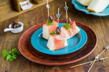 Aperatif, kavun ve prosciutto kahverengi ahşap arka planda mavi bir tabak. Abur cubur tarifleri. İtalyan Mutfağı