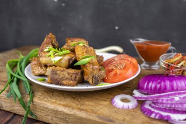 Sebzeli tabakta servis edilen kemik üzerinde ızgara domuz pirzolası. Koyu arkaplanda ızgara et..