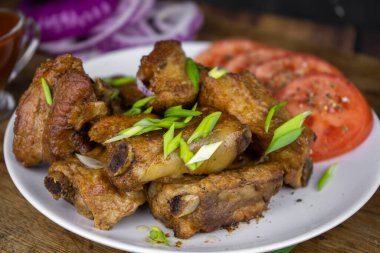 Sebzeli tabakta servis edilen kemik üzerinde ızgara domuz pirzolası. Koyu arkaplanda ızgara et..