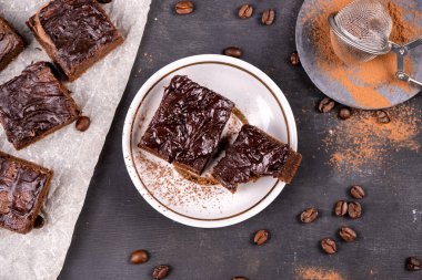 Kakaolu kekler erimiş siyah çikolatayla birlikte kare şeklinde dökülüyor. Siyah arka plan. Üst görünüm düzlüğü