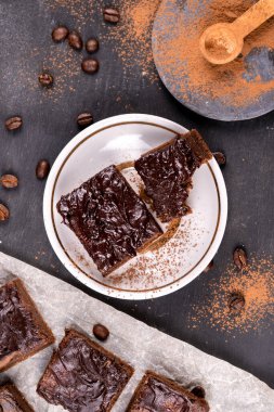 Kakaolu kekler erimiş siyah çikolatayla birlikte kare şeklinde dökülüyor. Siyah arka plan. Üst görünüm düzlüğü