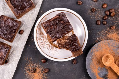 Kakaolu kekler erimiş siyah çikolatayla birlikte kare şeklinde dökülüyor. Siyah arka plan. Üst görünüm düzlüğü