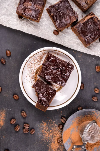 Kakaolu kekler erimiş siyah çikolatayla birlikte kare şeklinde dökülüyor. Siyah arka plan. Üst görünüm düzlüğü