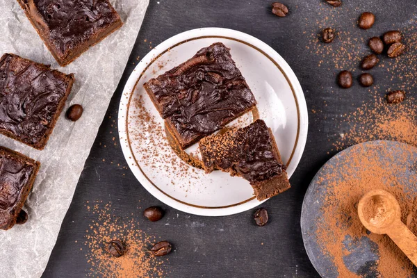 Kakaolu kekler erimiş siyah çikolatayla birlikte kare şeklinde dökülüyor. Siyah arka plan. Üst görünüm düzlüğü