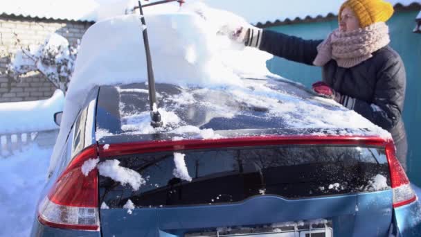 大雪过后 妇女用汽车刷子清扫汽车上的雪 — 图库视频影像