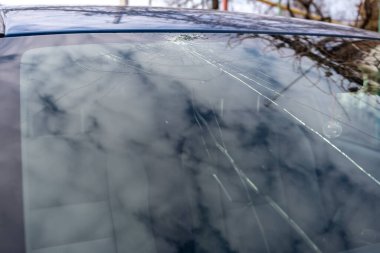 Kırık ön cam, bir sürü çatlak, küçük cam parçaları, hasarlı bir araba.