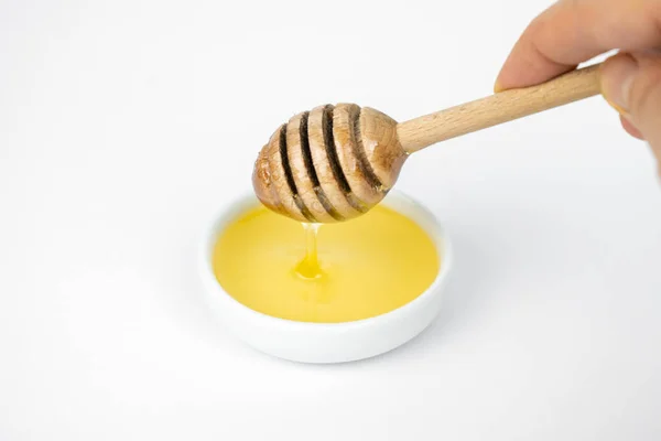 小さな白いプレートに木製の棒で注ぐ液体蜂蜜 — ストック写真
