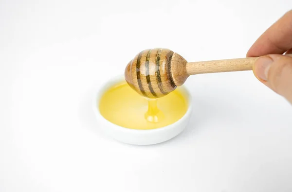 小さな白いプレートに木製の棒で注ぐ液体蜂蜜 — ストック写真