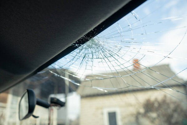 broken windshield with a lot of cracks and small glass pieces, damaged car