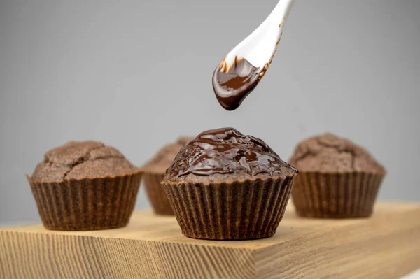 Nalít Roztavenou Čokoládu Čokoládově Hnědých Muffinů Dřevěnou Desku — Stock fotografie