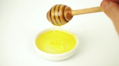 Sıvı bal küçük beyaz tabaktan tahta sopayla alınır.