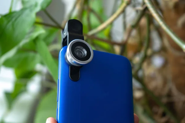 Overhead phone lens with clips on the blue modern smartphone. Extra macro camera for mobile device