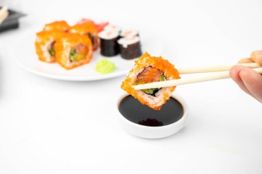 Bir tane bambu çubuklu California maki dürümü al ve soya sosunun içine koy. Pembe zencefil, wasabi. Asya yemekleri, Japon mutfağı geçmişi.