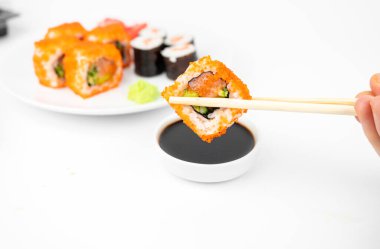 Bir tane bambu çubuklu California maki dürümü al ve soya sosunun içine koy. Pembe zencefil, wasabi. Asya yemekleri, Japon mutfağı geçmişi.