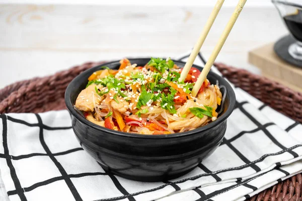 stock image Asian salad with rice noodles, vegetables, mushrooms, chicken and soy sauce. Funchose with white transparent noodles in black plate