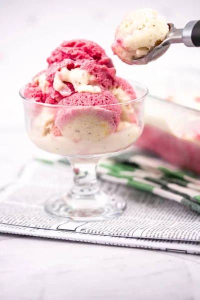 Strawberry frozen yogurt in glass bowl, ice cream balls, container with homemade sundae