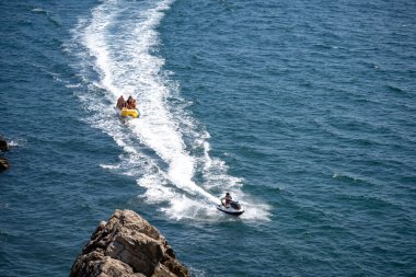 Muz teknesi suyuyla birlikte yüksek jet ski 'nin insansız hava aracı fotoğrafı. Tropikal mavi körfezde yüksek hızda seyahat eden sporlar, deniz suyu eğlencesi.
