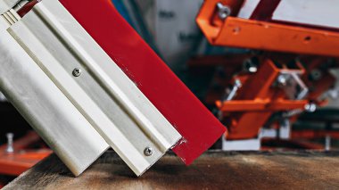 selective focus photo of a squeegee on wooden shelve of the print screening apparatus. serigraphy production. printing images on t-shirts by silkscreen method in a design studio clipart