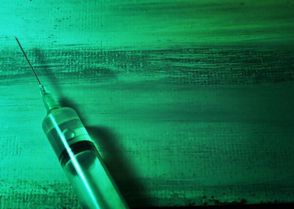 Injection syringe on a green, dark grunge background. With copy space for text