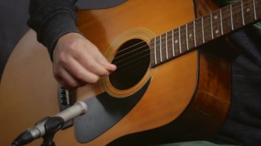 Akustik gitar çalıyorum. Gitarın gövdesine yakın çekim. Bir müzik videosu arka planı, konsept