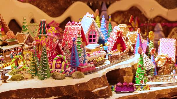 ジンジャーブレッドハウスと鉄道のおもちゃの都市。列車の運転手は素晴らしい子供の街を旅します。アイシング付きの食用ジンジャーブレッドメーカー。パノラマのクリスマスの装飾. — ストック動画