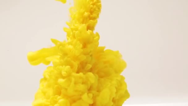 Αφηρημένο φόντο των πιτσιλιών του κίτρινου χρώματος στο νερό, μια έκρηξη του κίτρινου χρώματος, πιτσιλιές και διάδοση των φωτεινών χρωμάτων — Αρχείο Βίντεο