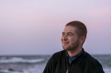 Denizin arka planında sakallı ve beyaz köpüklü dalgalarla gülümseyen beyaz bir adam. Seçici odak, yakın plan.