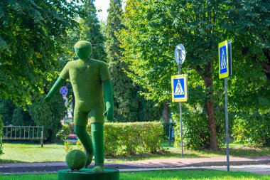 Yapay çim ve çim ağacından yapılmış topu olan bir futbolcu figürü. Seçici odak, yakın plan.