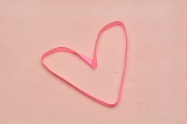 Beton ve alçıdan oluşan pembe arkaplan dokusunda kalp şeklinde ipek kumaş. Sevgililer Günü için konsept, aşk, düğün.