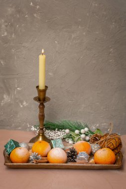 Eskimiş siyah şamdandaki alevli mum gri beton duvara karşı. Karda mandalina, kozalak ve kış tatilinde yulaf ezmeli kurabiye..