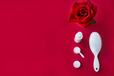 Mesajlar için kırmızı pankart. Saç bakım konsepti. Beyaz saç fırçası ve kozmetik ürünleri kadife masada. Üst görünüm, seçici odak.