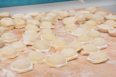 Hamur ve kıymadan ev yapımı hamur tatlısı pişirmek. Un ile yontulmuş ravioli. Yakın çekim, seçici odaklanma.